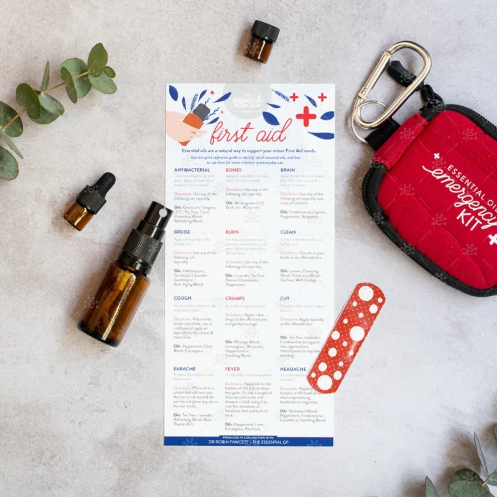 First Aid Needs infokort på engelsk med eteriske oljer, sprayflaske, oljeflaske, plaster og et førstehjelpsetui.